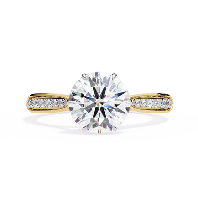 Gold ring with a large diamond and smaller diamonds on the band against a white background